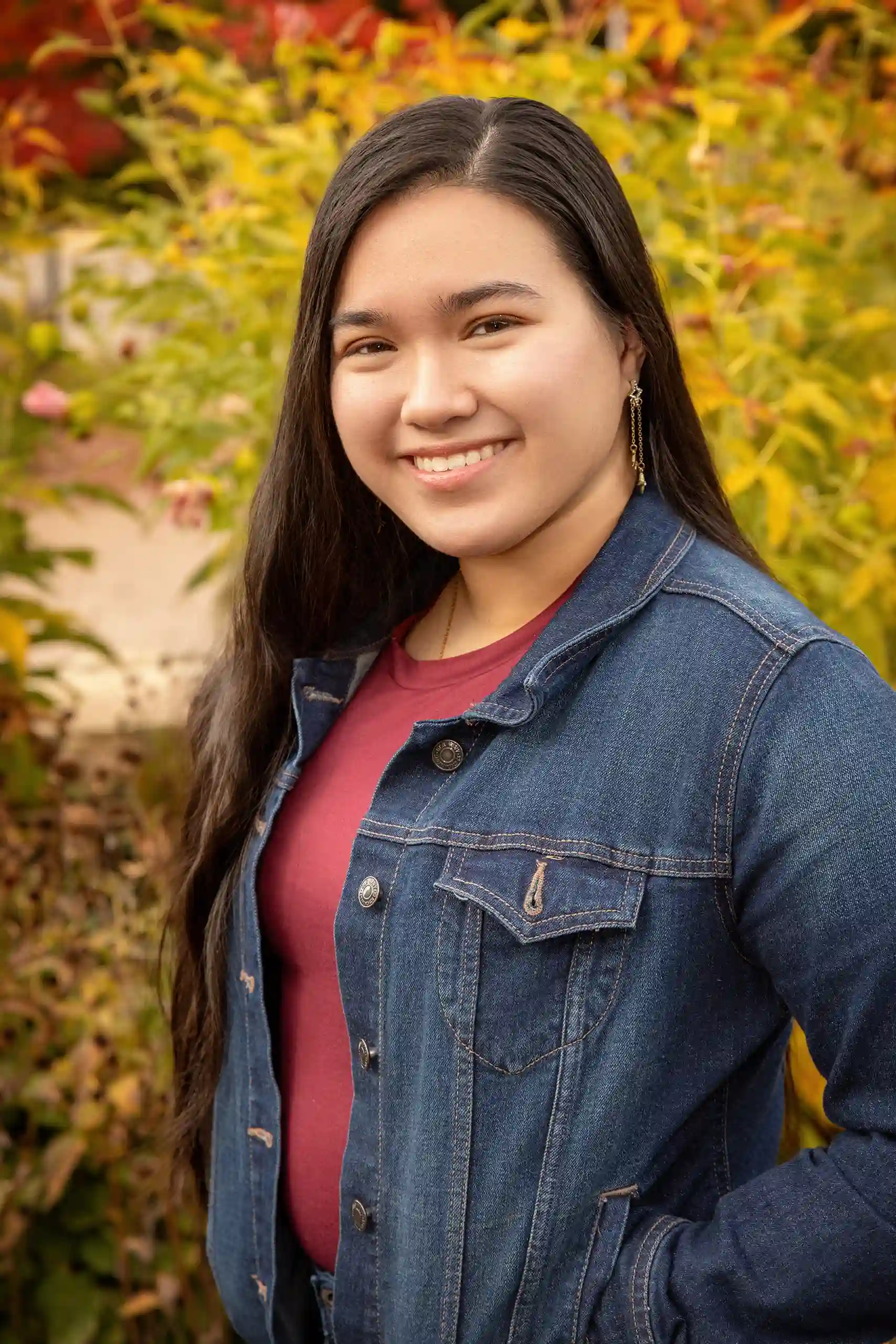 A professional individual portrait of a young woman in a denim jacket taken at an outdoor location in Ogden.