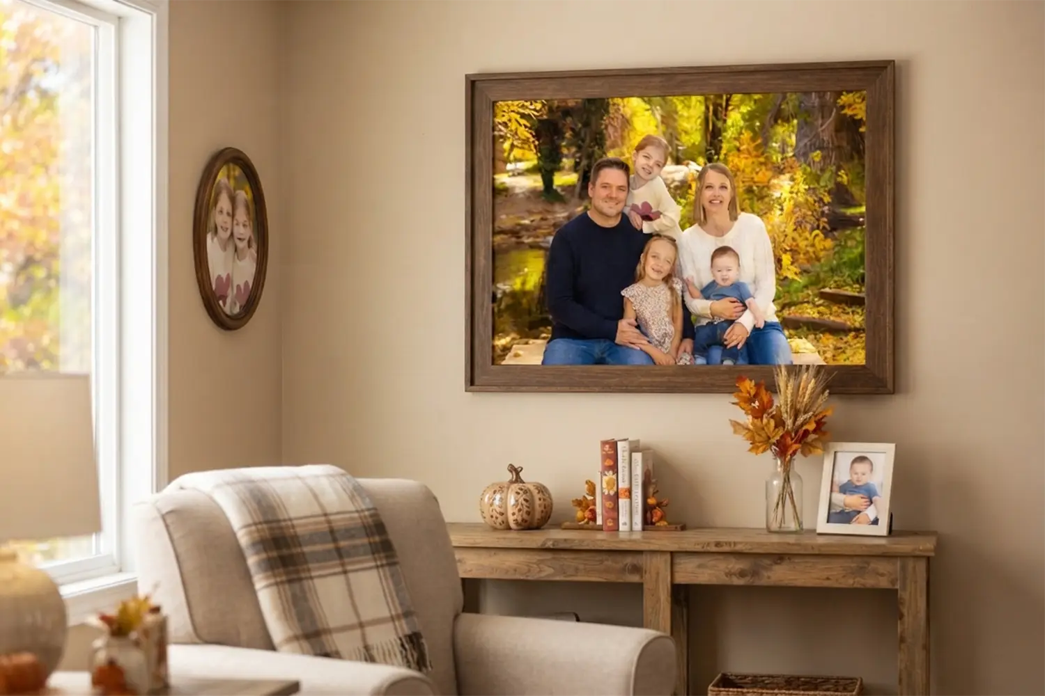 Family fall wall art A framed fall family portrait hanging on the living room wall above a wooden console table styled with a small pumpkin, dried floral arrangement, and a framed photograph.