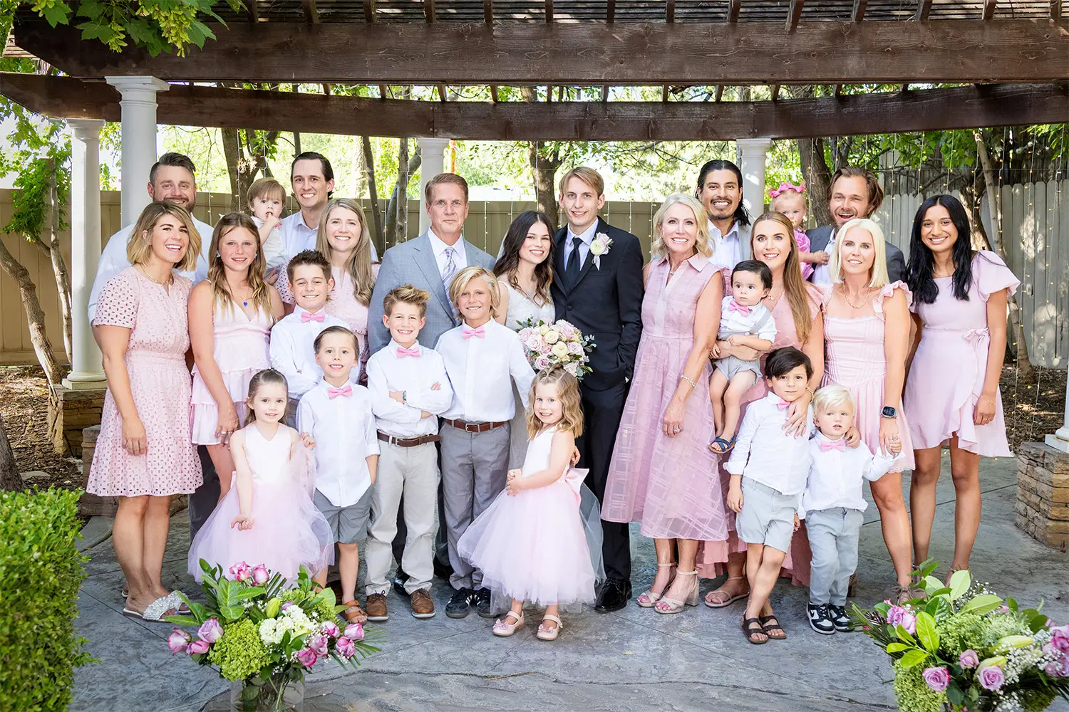Bride and groom posing with family members outdoors on a paved stone pathway
