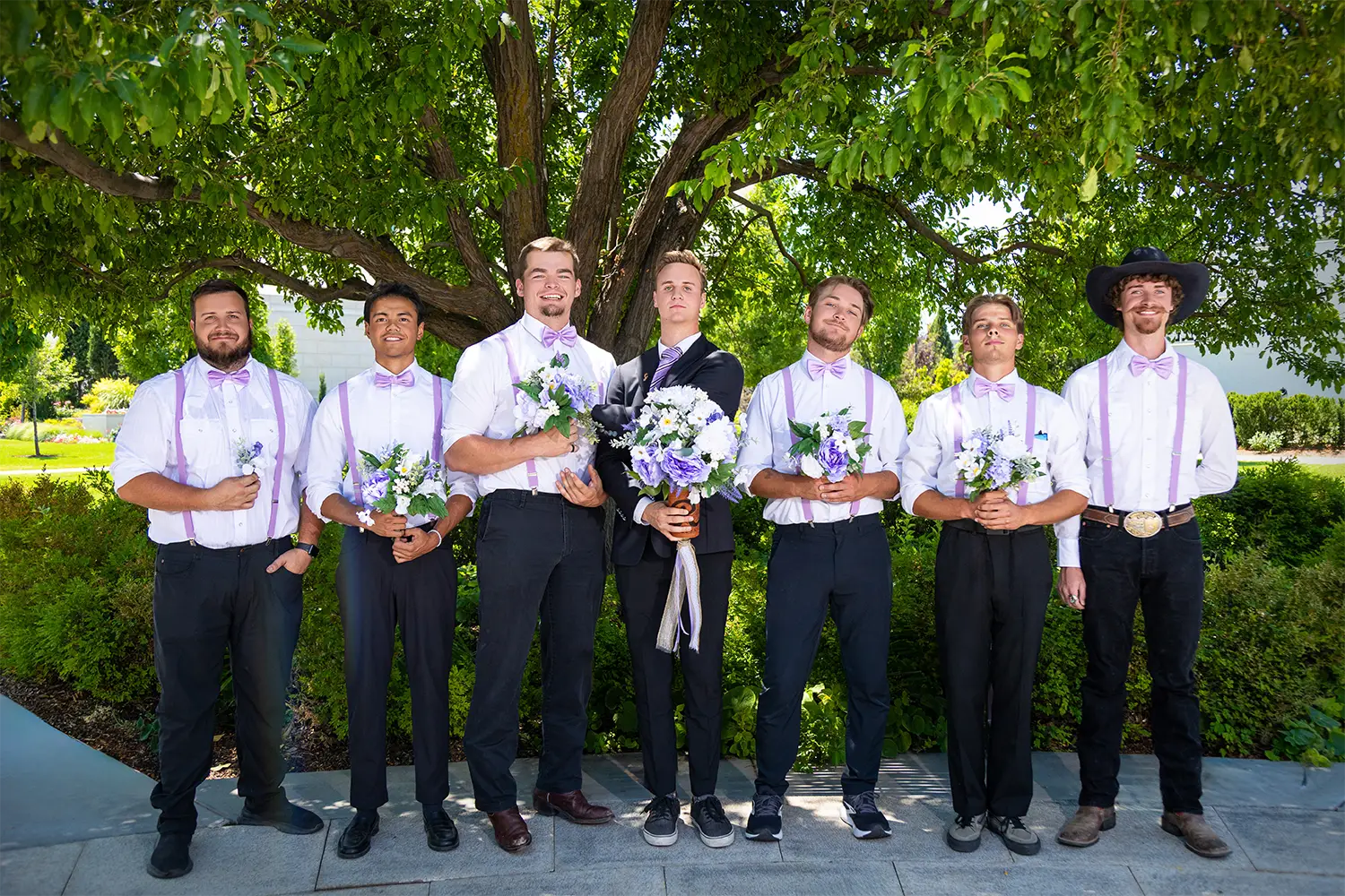 Groom and groomsmen posing outdoors together on a stone pathway