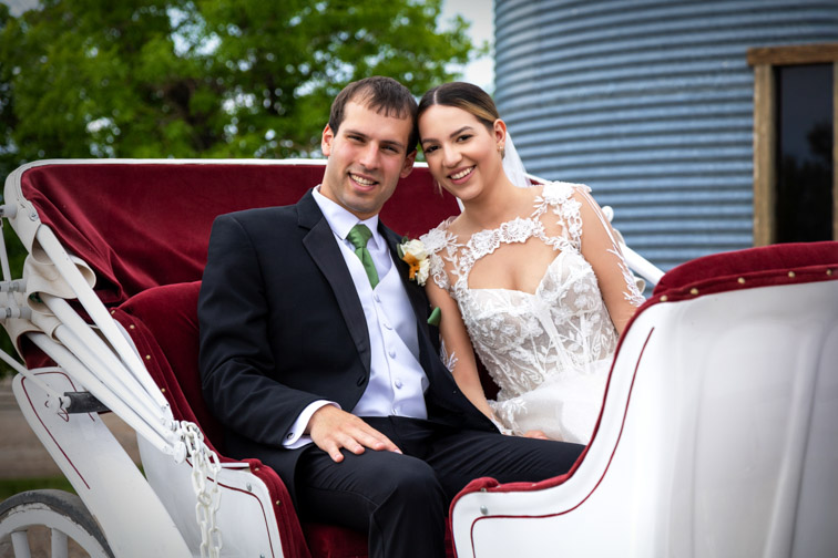 0 Bride and groom smiling together outdoors in a lush, green natural setting.