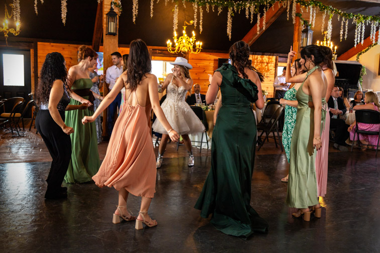 Bridesmaids in colorful dresses and wedding guests dancing indoors at a celebration