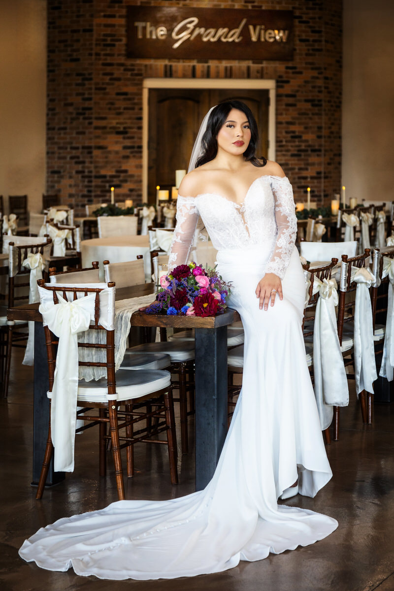 3603-wedding Bride sitting gracefully on indoor metal spiral stairs, holding a bouquet of flowers.